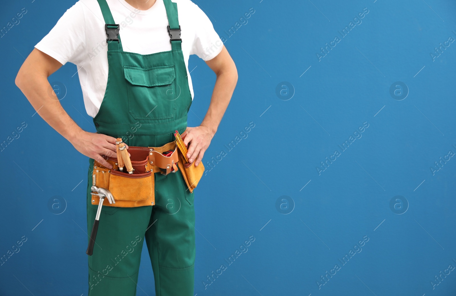 Photo of Carpenter with tool belt on blue background, closeup. Space for text