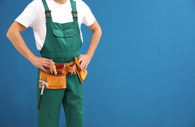 Carpenter with tool belt on blue background, closeup. Space for text
