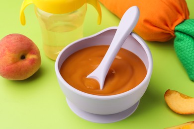 Healthy baby food in bowl on light green background, closeup