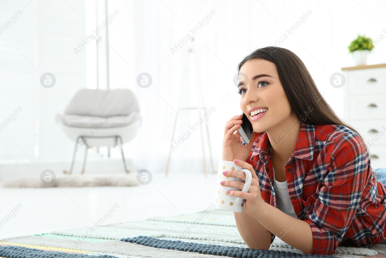 Photo of Attractive young woman using mobile phone while drinking coffee at home