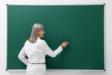 Professor explaining something at blackboard indoors, space for text