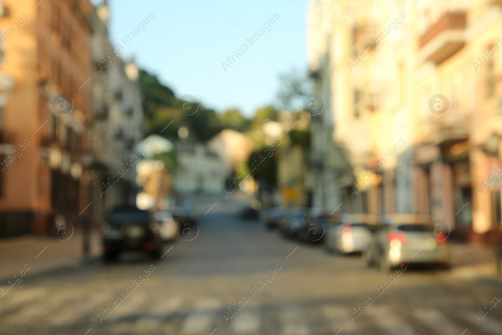 Photo of Blurred view of quiet city street with buildings and parked cars