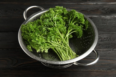 Colander with fresh green parsley on dark wooden table