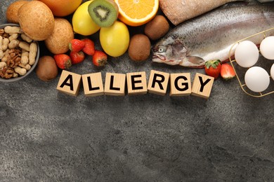 Image of Food allergy. Different fresh products and wooden cubes on grey table, flat lay with space for text