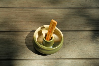 Photo of Palo santo stick in holder on wooden table, above view