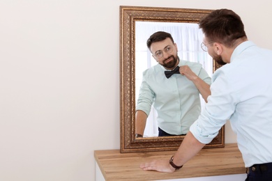 Photo of Young handsome man near mirror in makeup room