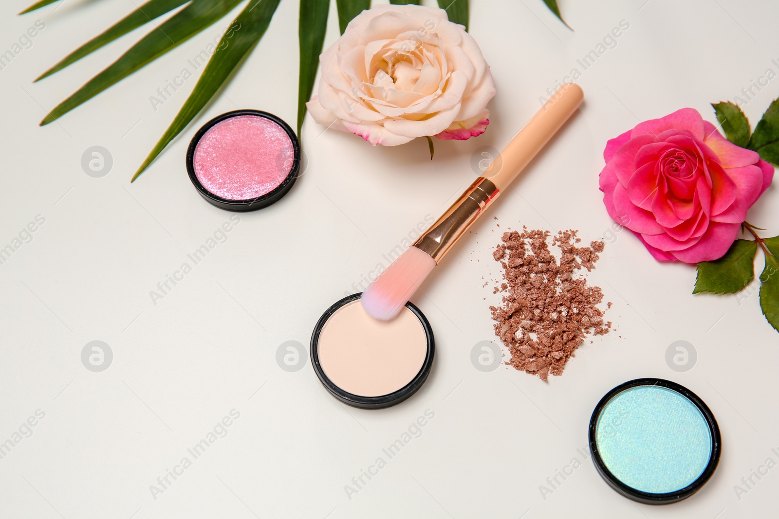 Photo of Composition with makeup brush, cosmetic products and roses on white background