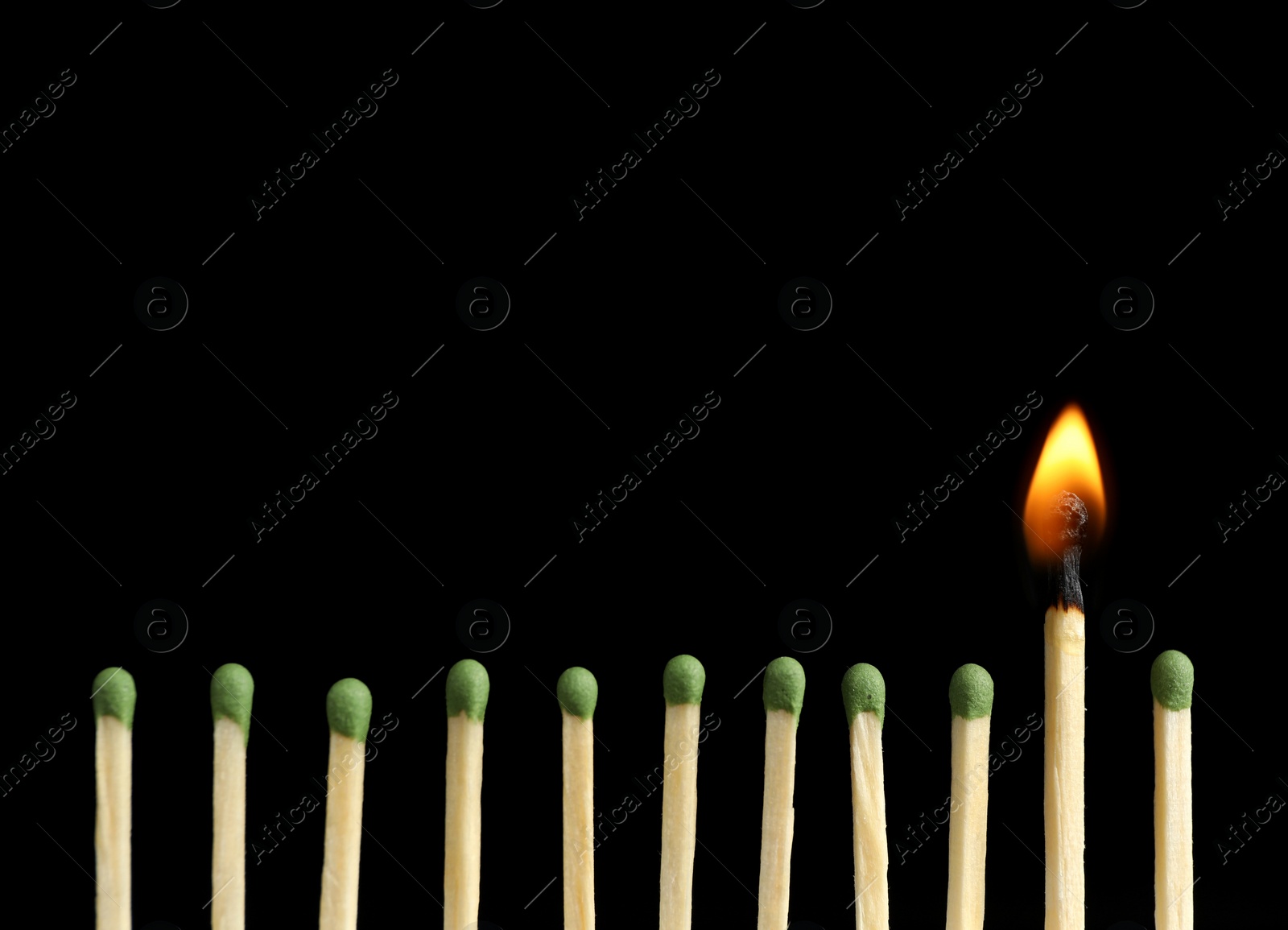 Photo of Burning match among unlit ones on black background, closeup