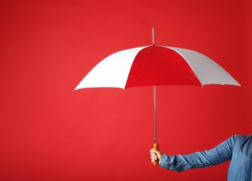 Photo of Woman holding modern colorful umbrella on red background, closeup. Space for text