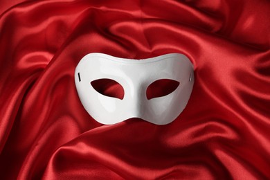 White theatre mask on red fabric, top view