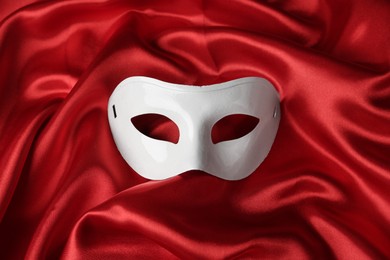 Photo of White theatre mask on red fabric, top view