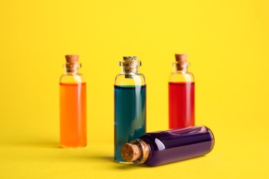 Photo of Bottles with different food coloring on yellow background