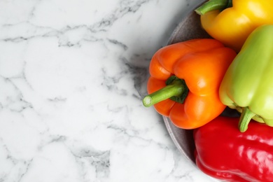 Photo of Plate with fresh bell peppers on marble table, top view. Space for text