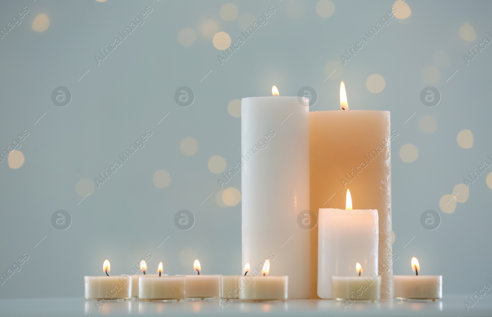 Photo of Many burning candles on table against blurred background with bokeh effect