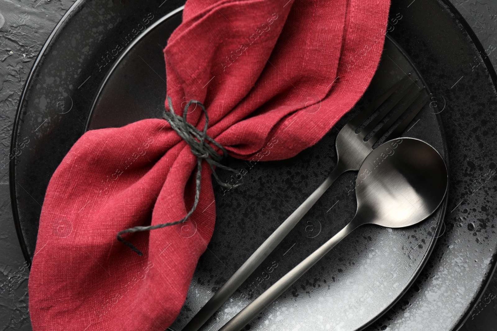 Photo of Stylish setting with cutlery, napkin and plates on dark textured table, top view