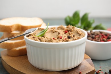 Delicious meat pate with spices, fresh bread and knife on wooden board, closeup