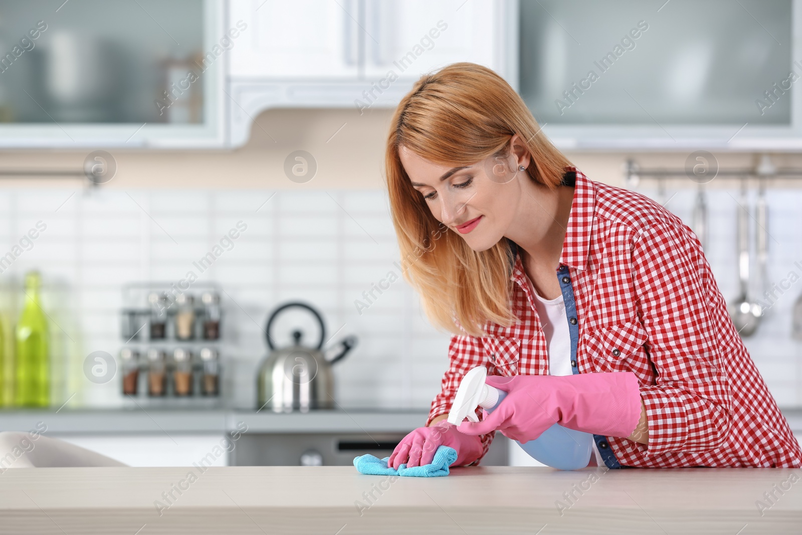 Photo of Woman cleaning table with rag in kitchen