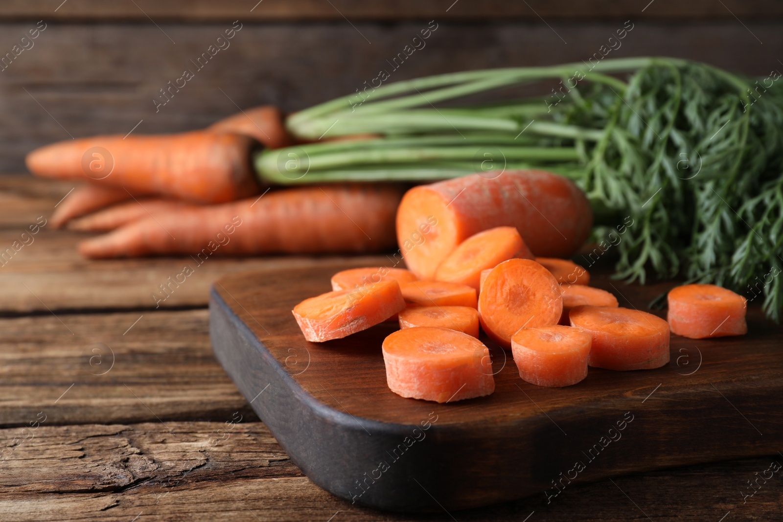 Photo of Fresh cut carrot on wooden table, closeup