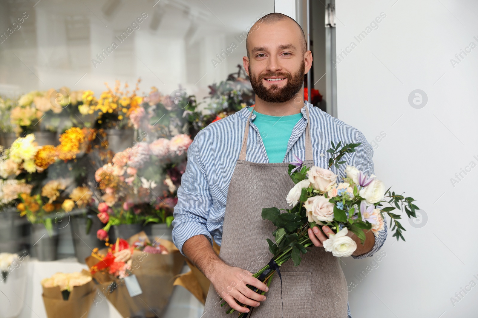 Photo of Professional florist with bouquet of fresh flowers in shop