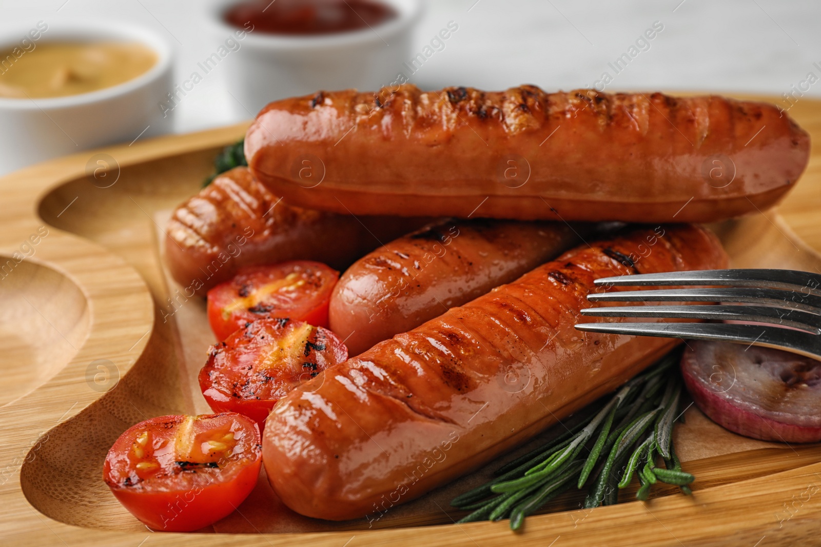 Photo of Delicious grilled sausages on wooden tray, closeup. Barbecue food