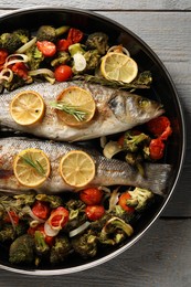 Photo of Baked fish with vegetables, rosemary and lemon on grey wooden table, top view