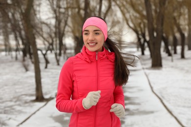 Happy woman running in winter park. Outdoors sports exercises