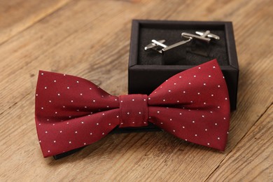 Photo of Stylish red bow tie and box of cufflinks on wooden background