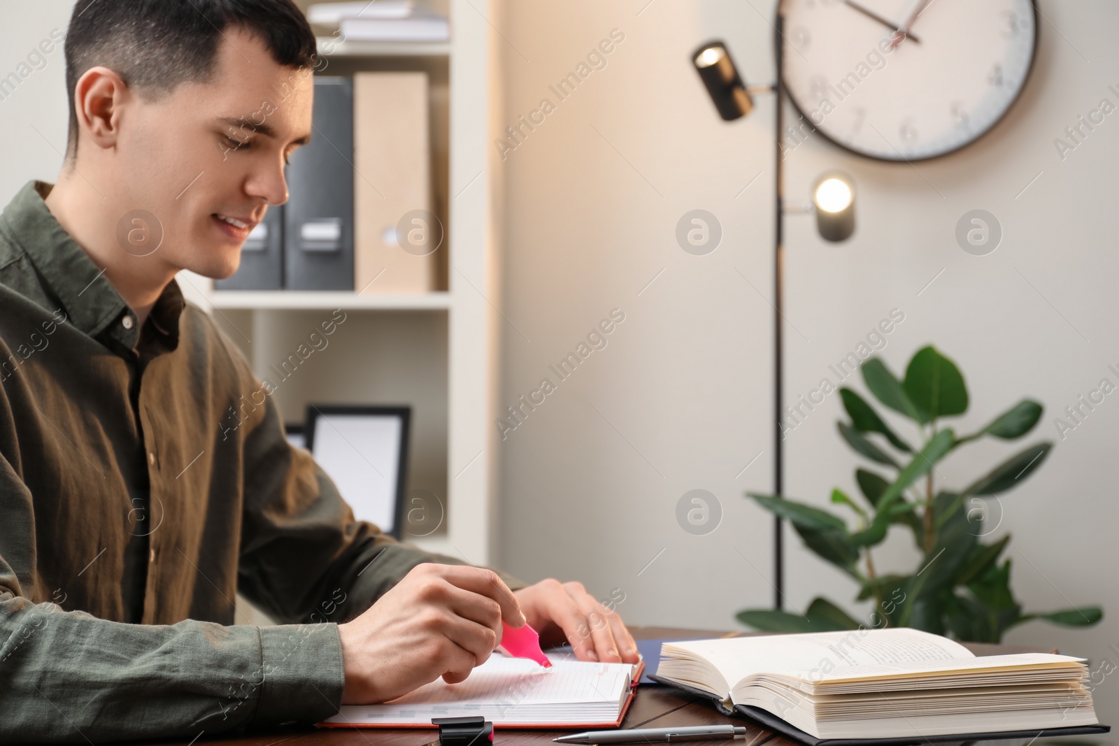 Photo of Man taking notes at wooden table in office