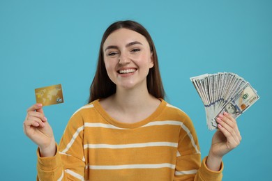 Happy woman with credit card and dollar banknotes on light blue background