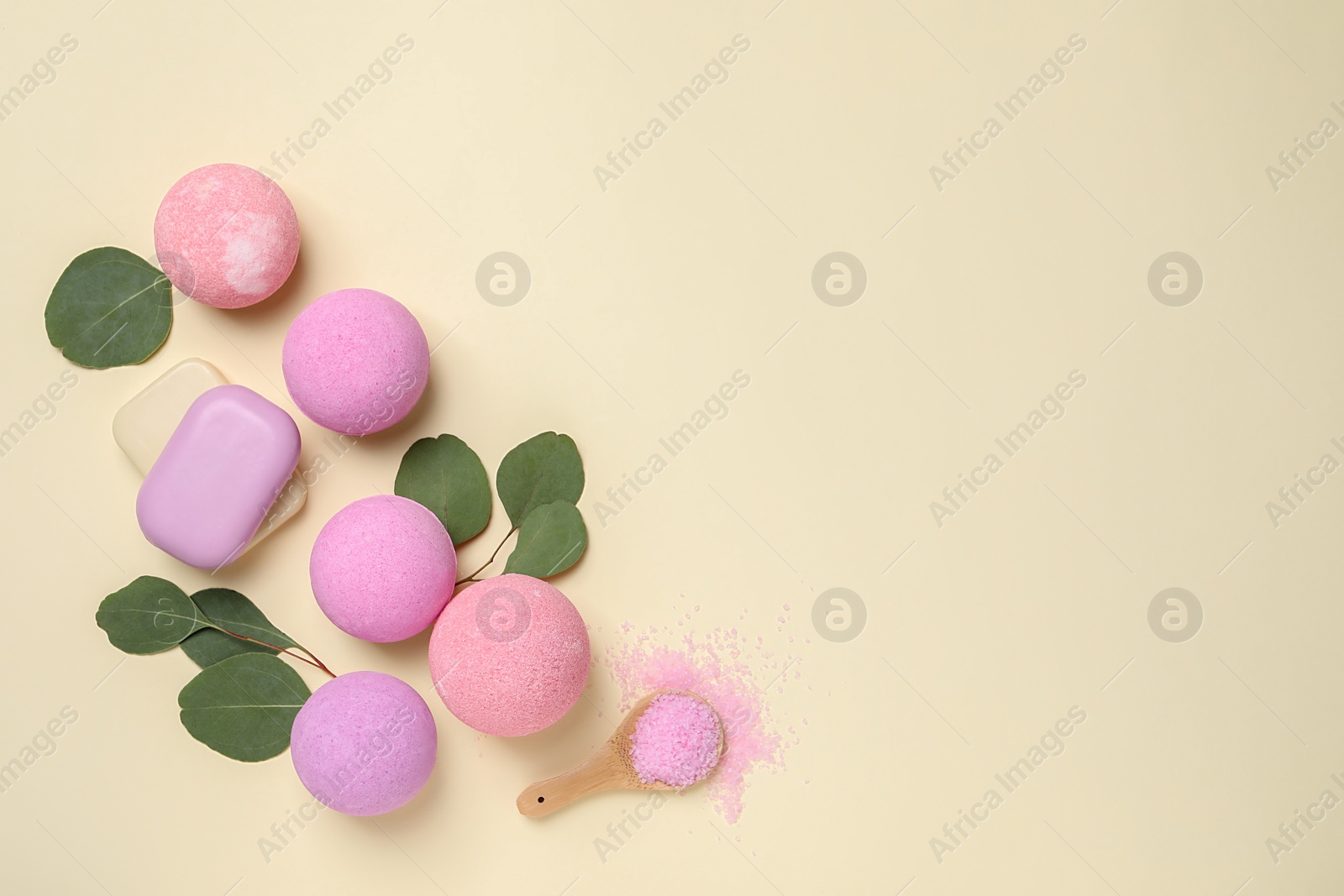 Photo of Bath bombs, eucalyptus leaves, sea salt and soap bars on beige background, flat lay. Space for text
