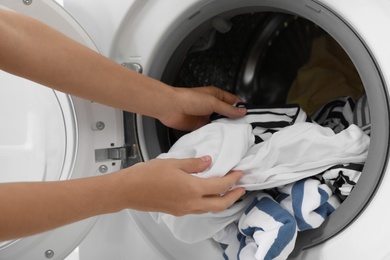 Photo of Woman taking clothes out of washing machine, closeup. Laundry day