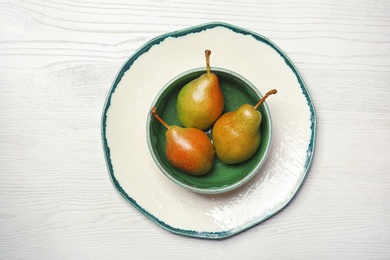 Photo of Dishware with pears on wooden background, top view