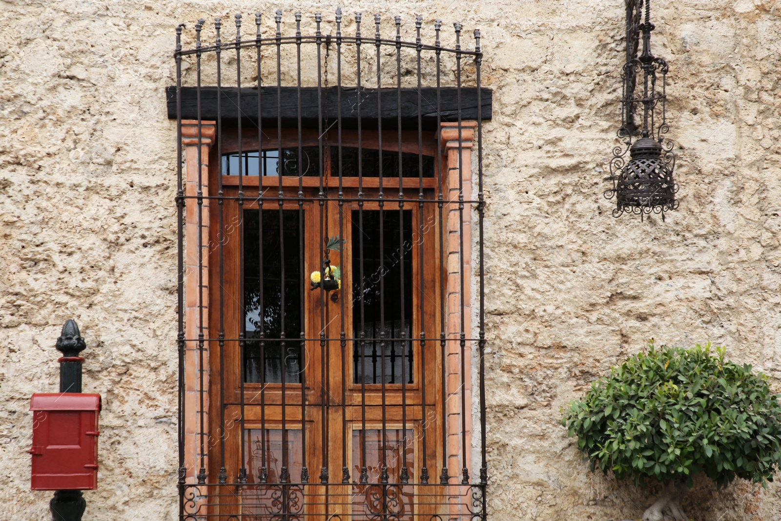 Photo of Entrance of residential house with wooden door, mailbox and steel grilles