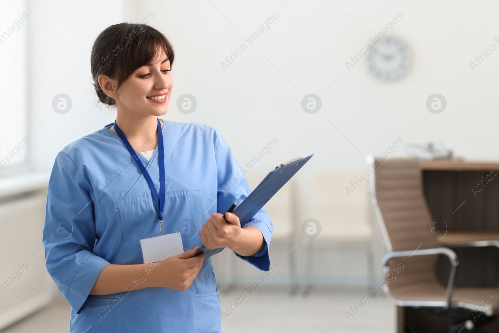 Photo of Portrait of smiling medical assistant with clipboard and pen in hospital. Space for text