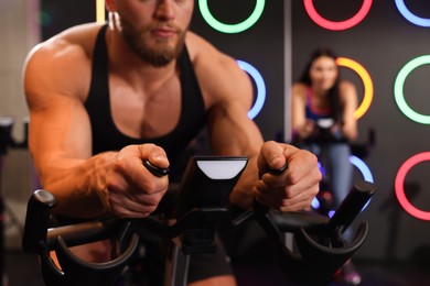 Photo of Young man training on exercise bike in fitness club, closeup