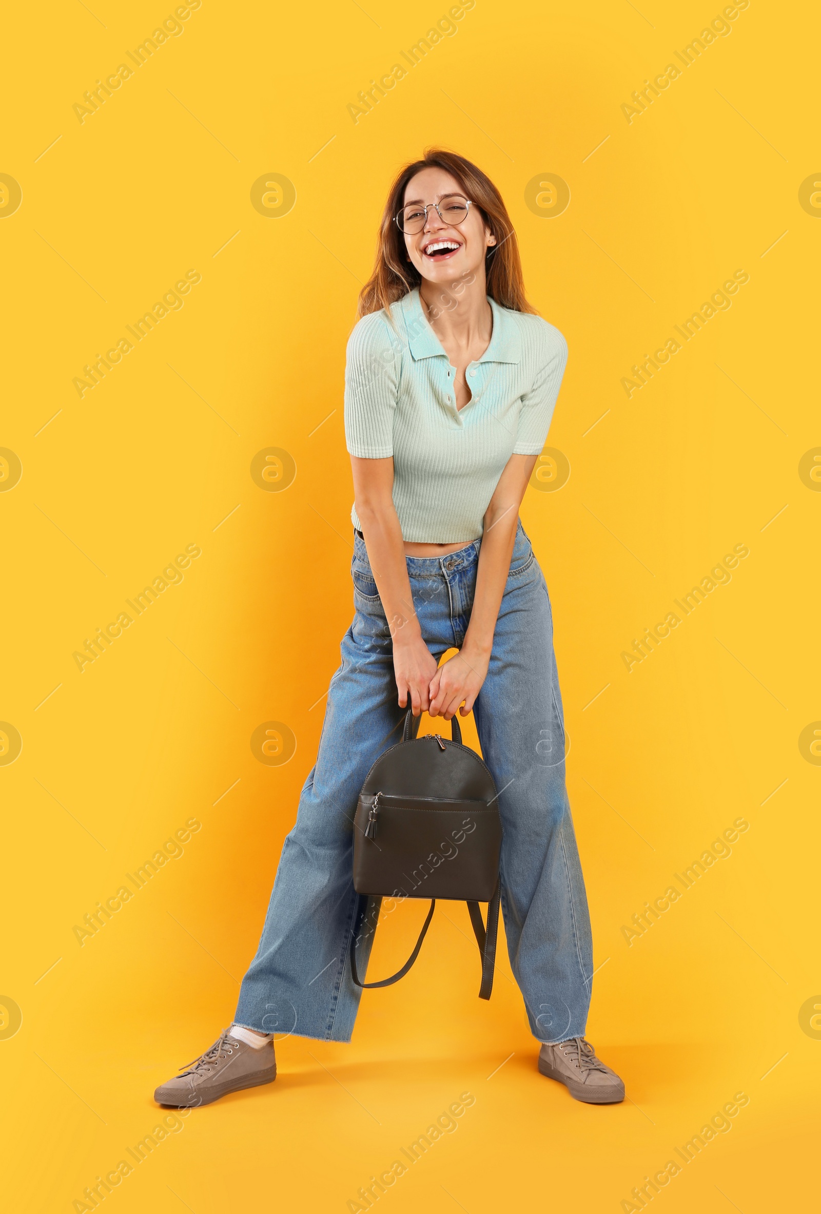 Photo of Happy woman with backpack on yellow background