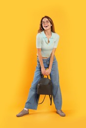 Happy woman with backpack on yellow background