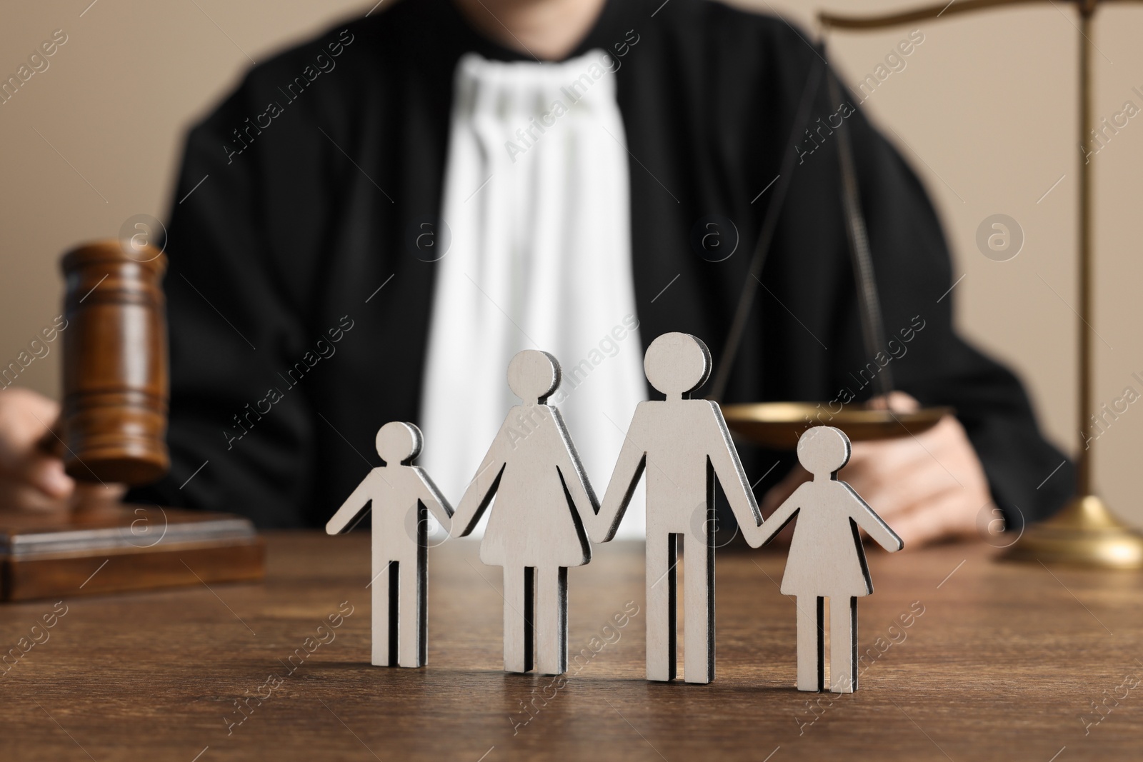 Photo of Family law. Judge with gavel and scales of justice sitting at wooden table, focus on figure of parents and children