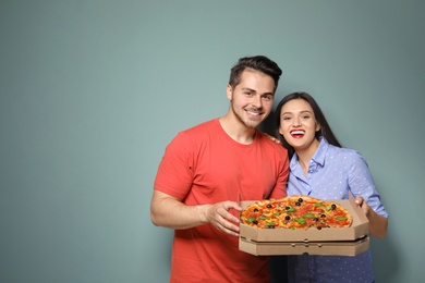 Photo of Attractive young couple with delicious pizza on color background