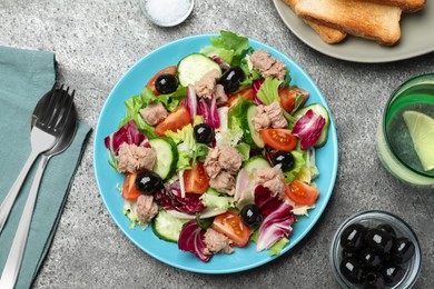 Plate of delicious salad with canned tuna and vegetables served on grey table, flat lay