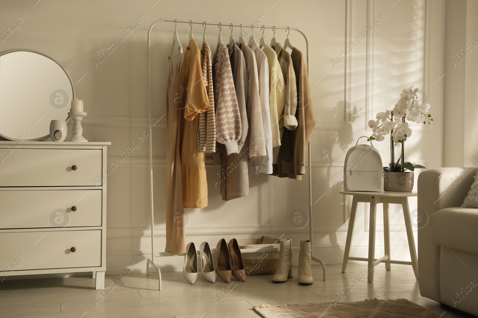 Photo of Modern dressing room interior with stylish clothes, shoes and beautiful orchid flowers