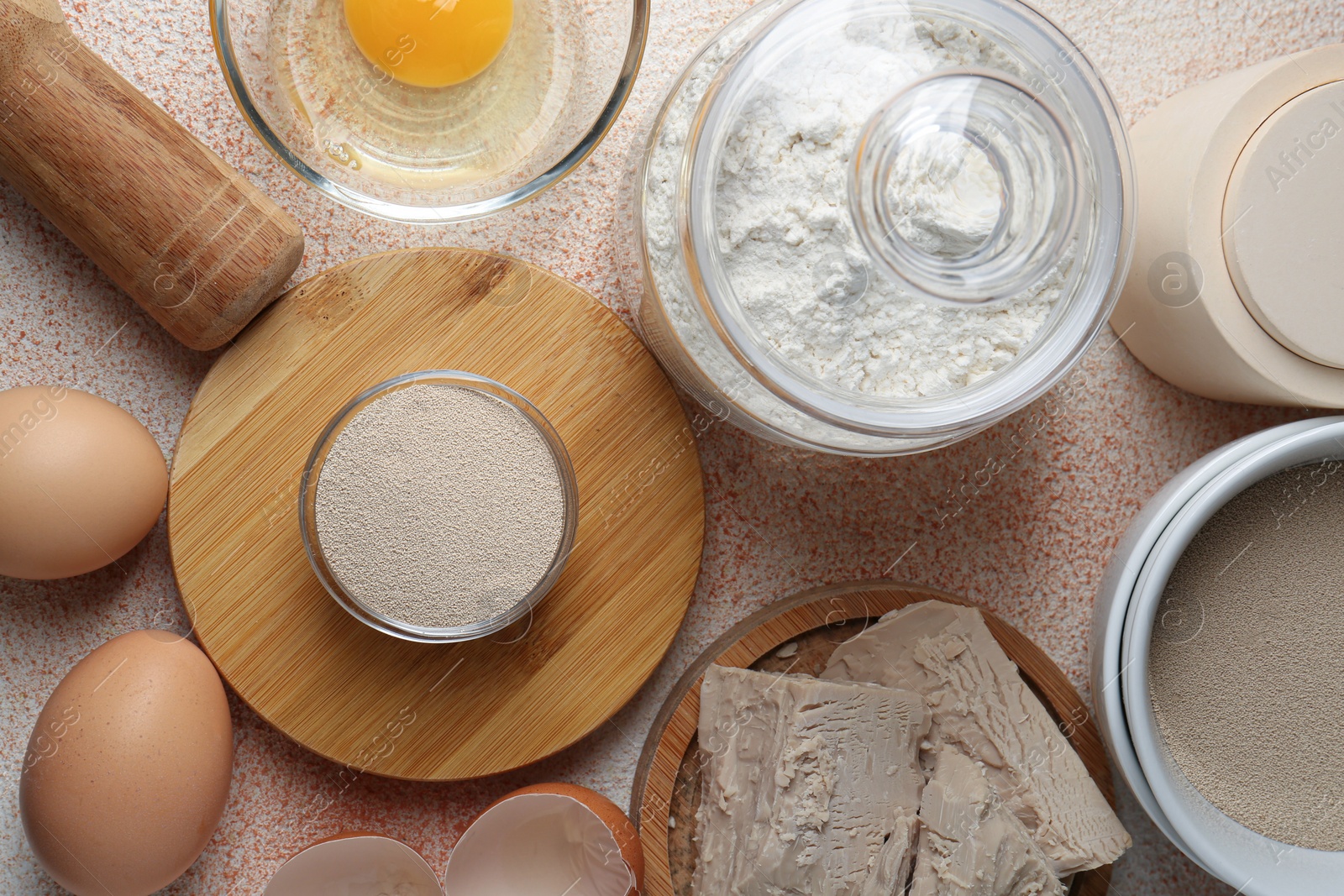 Photo of Different types of yeast, flour and eggs on orange textured table, flat lay