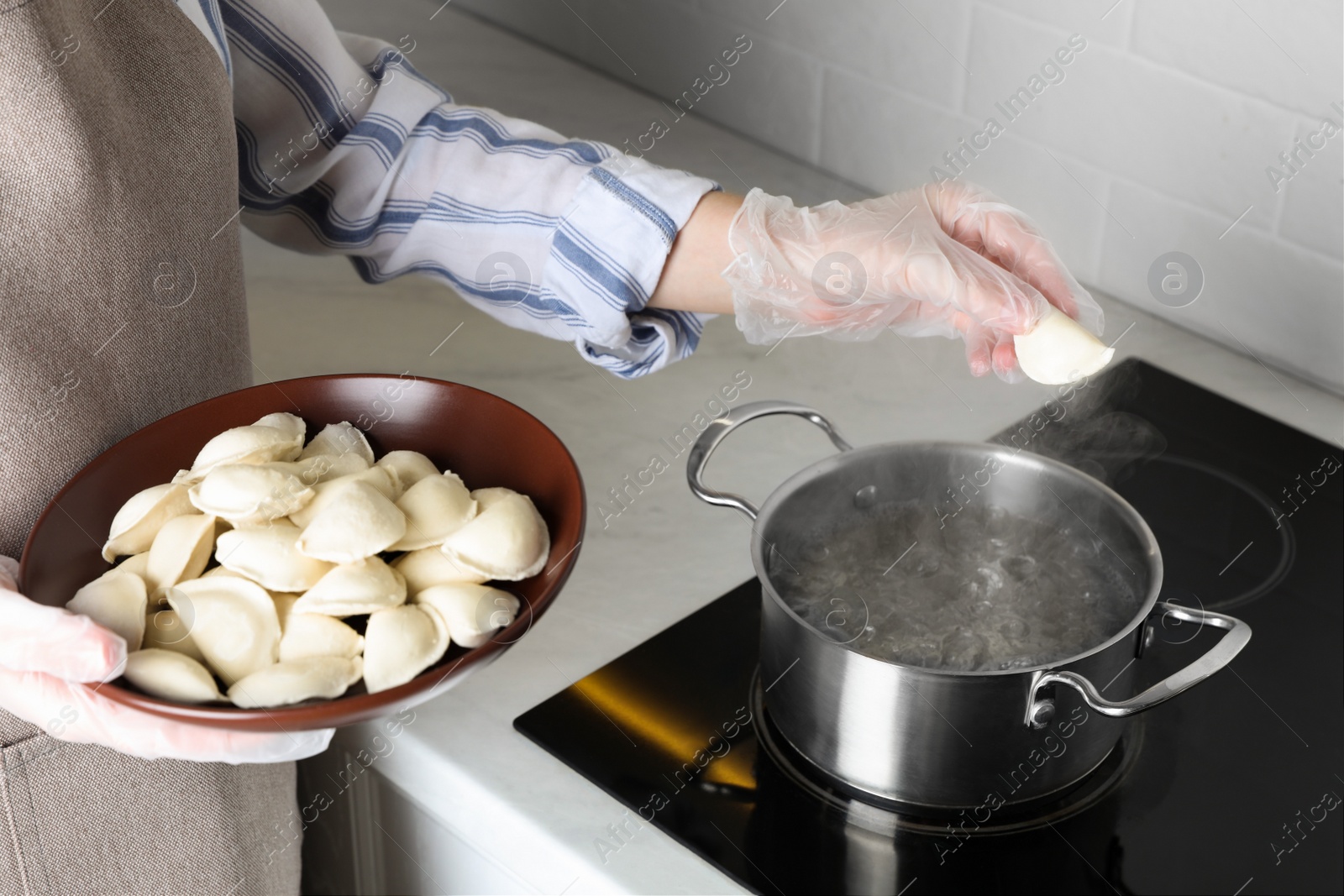 Photo of Woman cooking delicious dumplings in kitchen, closeup