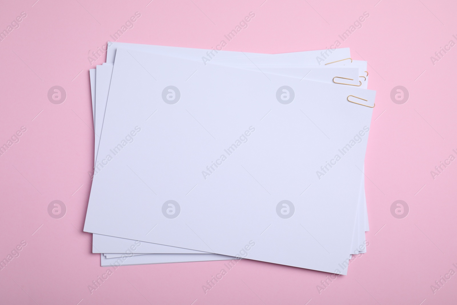 Photo of Sheets of paper with clips on pink background, top view