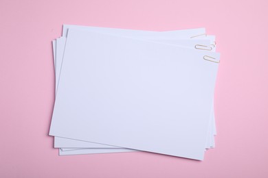 Photo of Sheets of paper with clips on pink background, top view