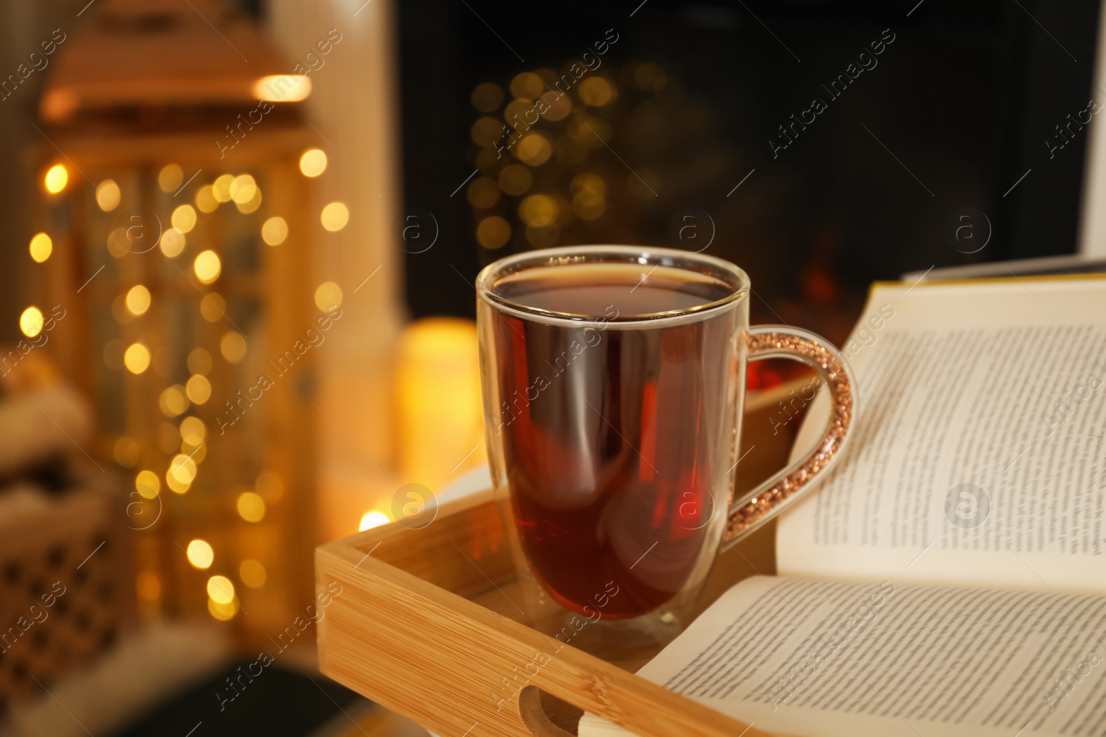 Photo of Cup of tea and book on wooden tray indoors