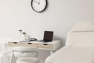 Modern medical office with doctor's workplace and examination table in clinic