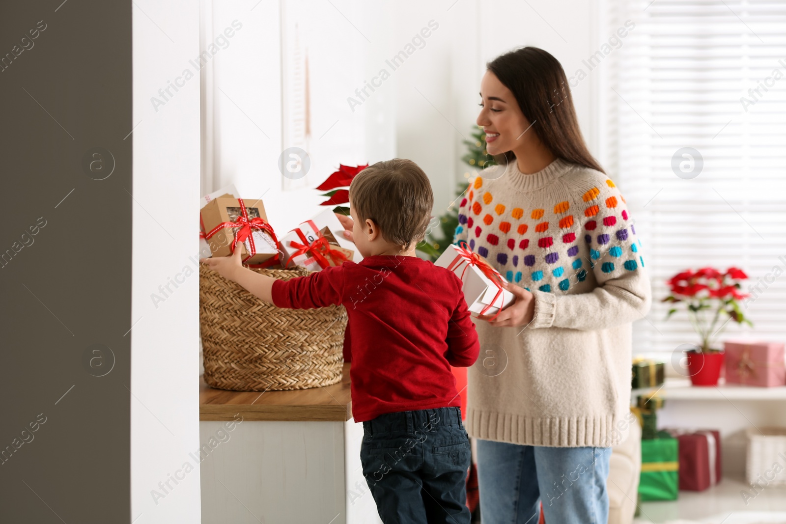 Photo of Mother and son with Christmas gifts at home. Advent calendar in basket