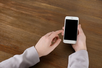 Photo of Woman using mobile phone at table, closeup with space for design