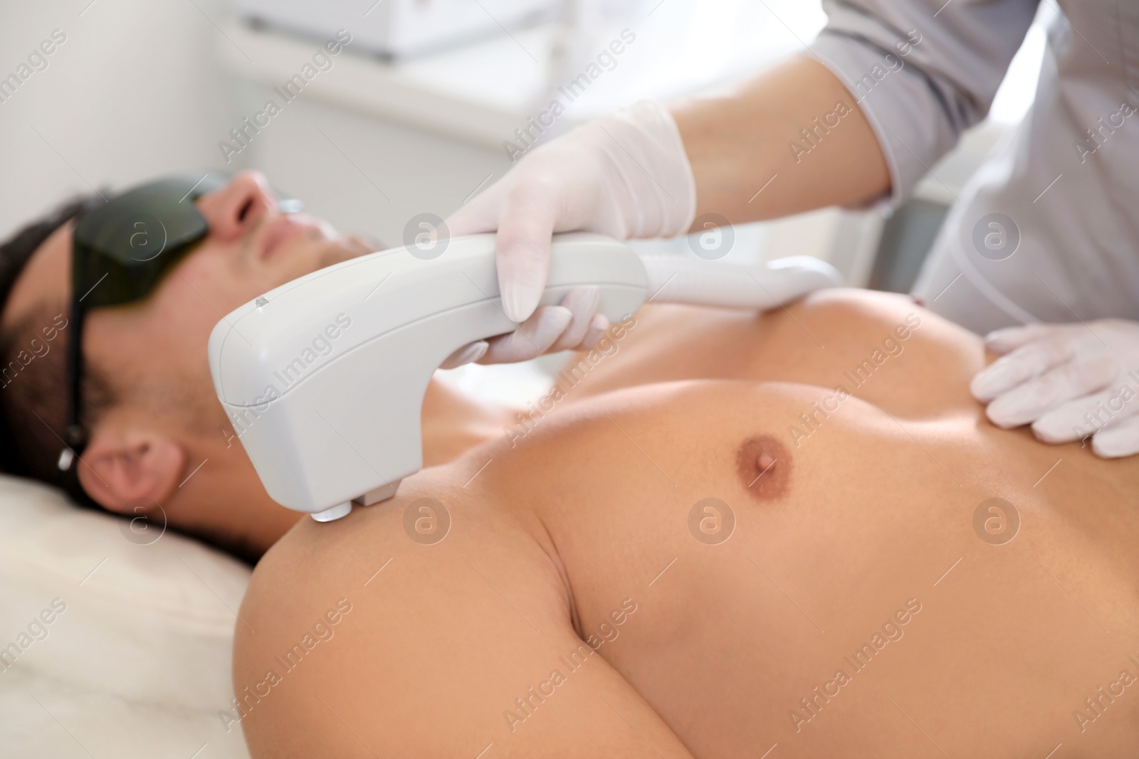 Photo of Young man undergoing laser epilation procedure in beauty salon, closeup